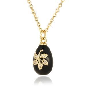 Macro view of black enamel egg pendant with gold flower inlay and zircon crystals