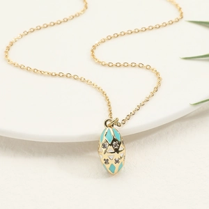 Elegant gold egg pendant necklace with sky blue enamel and crystals on white display