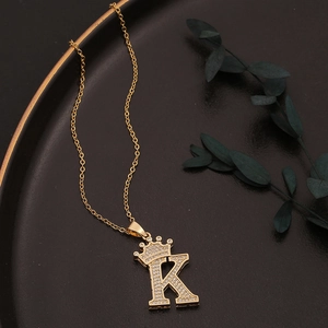 Goldene Halskette mit Kronen-Buchstabe K und Zirkonia auf elegantem schwarzem Tablett