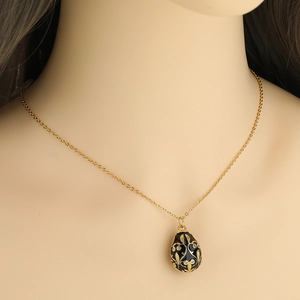 Detail of Russian egg pendant necklace with black enamel and gold floral engraving