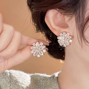 Eleganti orecchini a fiore dorati con zirconi scintillanti indossati da modella