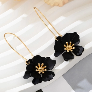 Detail of matte black floral earrings with golden stamens and long curved ear hooks