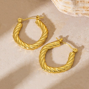 Detail shot of golden twisted hoop earrings with a textured woven metal finish
