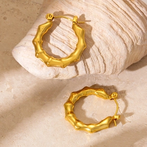 Detailed close-up of golden bamboo hoop earrings on natural stone for texture display