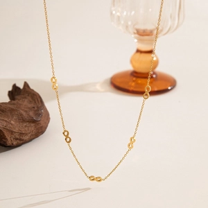 Detailed close-up of a gold-plated infinity link bracelet on warm aesthetic background