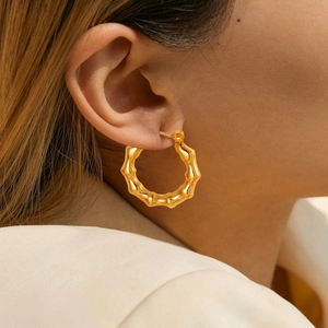 Detailed view of gold bamboo texture hoop earrings worn on ear showing vintage metallic finish