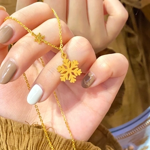 Polished gold snowflake pendant necklace on a titanium steel chain worn on the hand