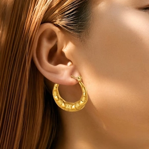 Close-up of gold chunky hoop earring featuring a delicate mesh woven texture on model