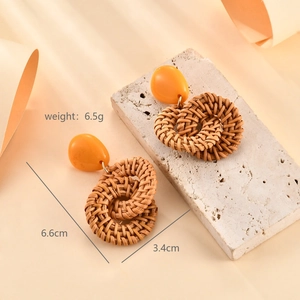 Detail view of woven raffia flower earrings with orange beads and size measurements