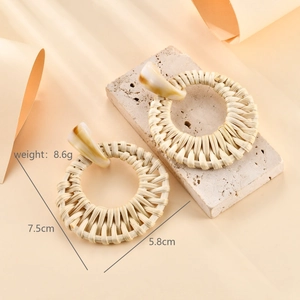 Detail view of woven raffia hoop earrings on stone with 5.8cm size and 8.6g weight info