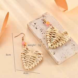 Detail of handmade raffia heart earrings with beads showing 8cm length dimensions