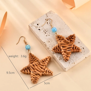 Detailed view of handmade raffia star earrings with blue beads and golden hooks