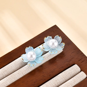Primer plano de pendientes de flores con pétalos azul claro y bordes dorados