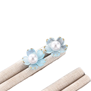 Elegantes pendientes de flores en esmalte azul con bordes dorados y perlas blancas