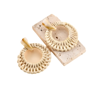 Handmade raffia hoop earrings with woven texture and amber resin detail on stone