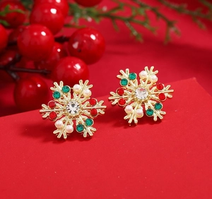 Detailed close-up of Christmas snowflake earrings with red green stones and pearls