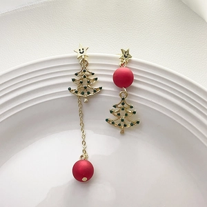 Detailed shot of asymmetric Christmas tree earrings with red beads and green crystals