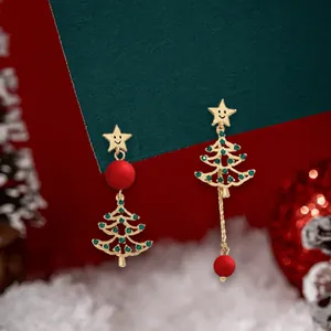 Detail of asymmetric Christmas tree earrings with gold stars and festive red beads