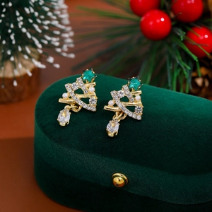 Close-up of Christmas tree earrings with white pearls on a green velvet jewelry box