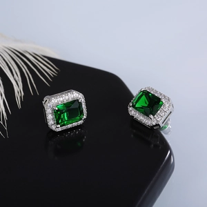 Detail of emerald-cut green zircon stud earrings with a sparkling halo design