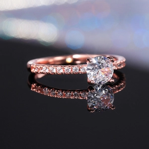 Dettaglio anello di fidanzamento in oro rosa con zircone e pavé di diamanti su specchio
