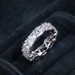 Macro shot of triangle-cut cubic zirconia eternity ring on navy velvet display