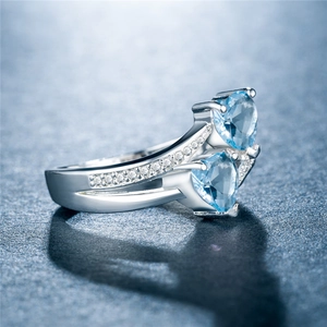 Makroansicht des blauen Doppelherz-Zirkonia-Rings mit gekreuzten Pavé-Bändern