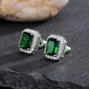 Macro shot of emerald-cut green stone earrings with white halo zircon settings