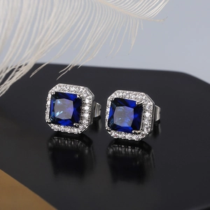 Macro shot of square cut blue zircon earrings with halo diamond setting on black mirror