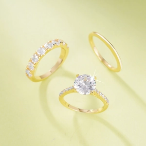 Dreiteiliges vergoldetes geometrisches Ring-Set mit Zirkonia-Steinen auf hellgrünem Grund