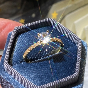 Macro di un anello di fidanzamento in oro e zirconi in una scatola di velluto blu