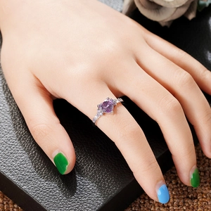 Elegant heart-shaped purple crystal ring with small side stones worn on finger
