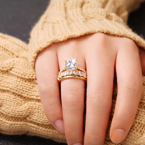 Nahaufnahme eines dreiteiligen Goldring-Sets mit runden Zirkonia auf einem Pullover-Hintergrund