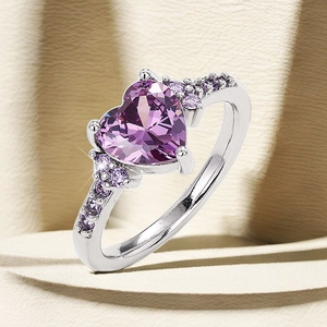 Macro detail of silver heart-cut purple zirconia ring with accent stones on light background