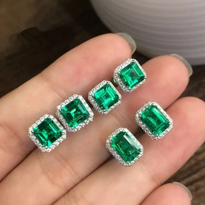 Handheld view of silver square emerald-cut green zircon stud earrings with halo diamonds