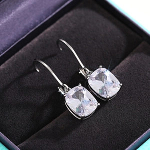 Macro shot of cushion-cut blue gemstone earrings with claw setting on black velvet