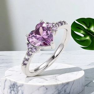 Macro detail of silver ring with heart-shaped purple stone on marble stand