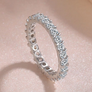 Macro detail of sparkling full circle claw-set eternity ring on soft pink background