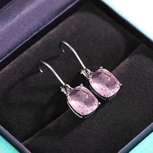 Detailed macro of cushion-cut pink gemstone drop earrings in a purple velvet jewelry box