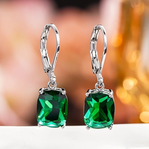 Detailed close-up of emerald green square-cut stone earrings with silver lever-back hooks