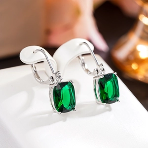Detail view of rectangular emerald green gemstone drop earrings with silver prongs