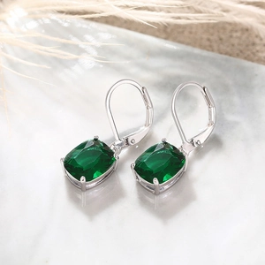 Detailed view of silver lever-back earrings featuring emerald green cushion cut crystals