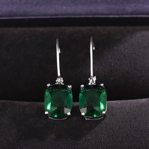 Macro detail of emerald-cut blue topaz earrings in silver claw setting on black velvet