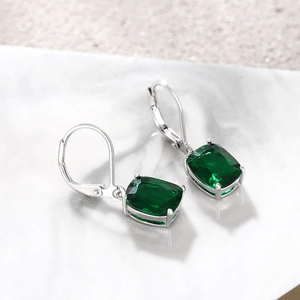 Detailed view of silver lever-back earrings with faceted rectangular green stones