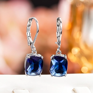 Macro shot of cushion-cut blue faux topaz earrings with silver lever-back setting