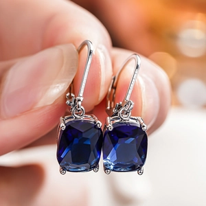 Macro shot of square blue faux topaz earrings with silver French hook in four-prong setting