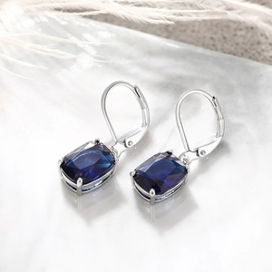 Macro detail of rectangle cut blue topaz dangle earrings with silver lever-back closure