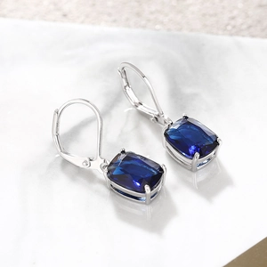 Detail view of deep blue rectangular gemstone drop earrings with silver lever-back closure