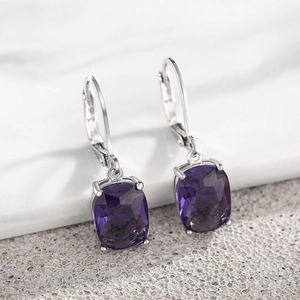 Macro detail of silver dangle earrings with square purple gems in four-prong settings