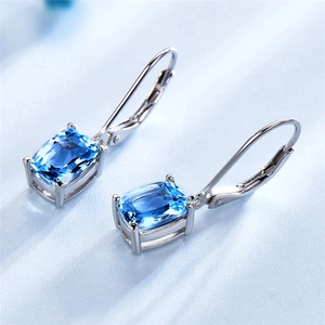 Macro detail of rectangle blue topaz earrings featuring four-prong silver settings